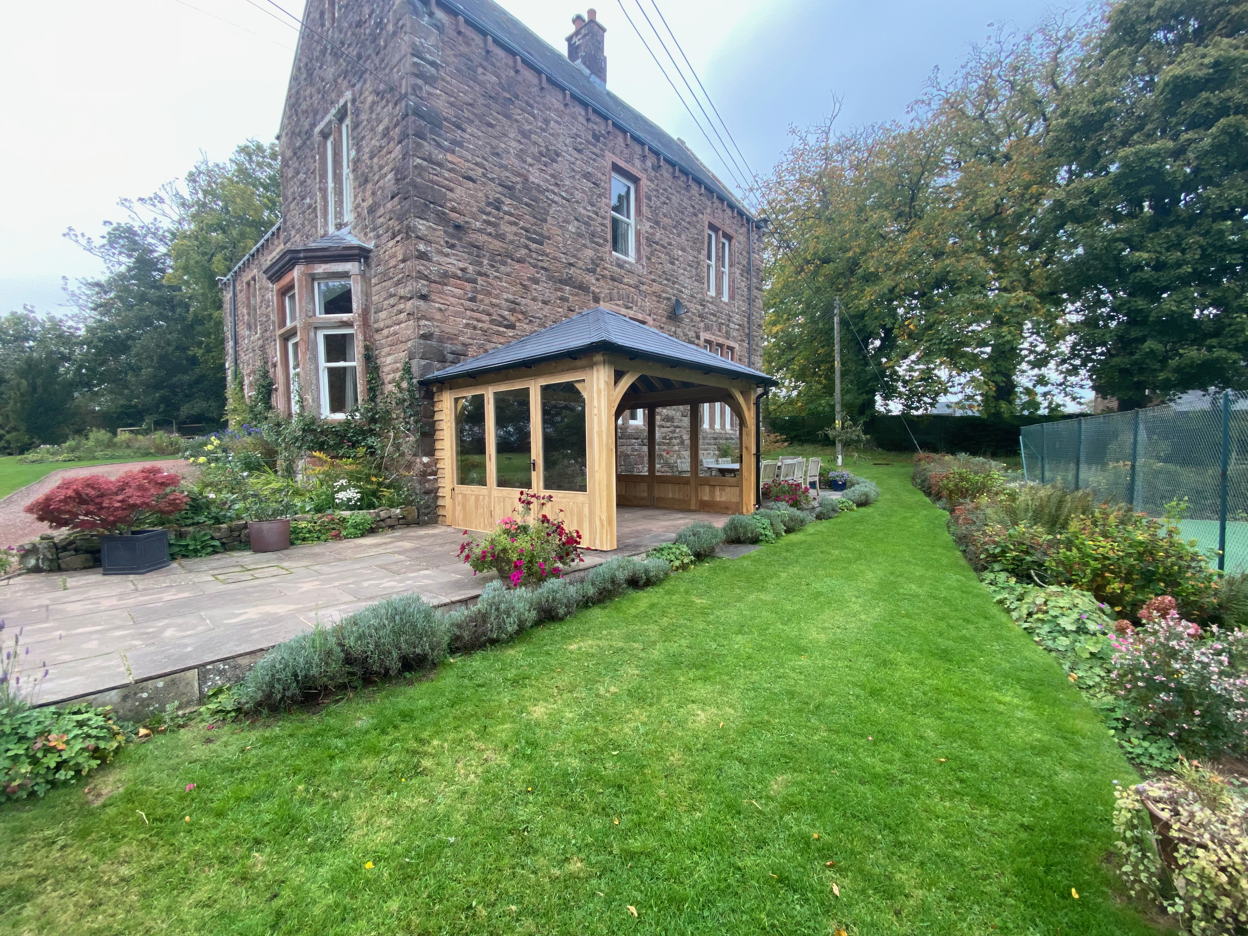 Oak framed gazebo handmade by Woodstyle Joinery, fitted to a sandstone house in Cumbria